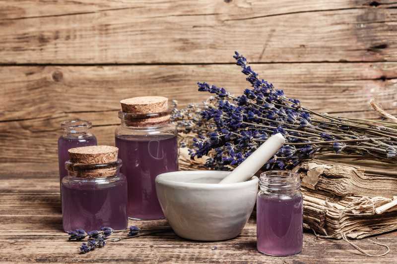 Dried lavender flowers in a in a mortar and pestle with bottle of essential lavender oil | Natural Mosquito Repellents