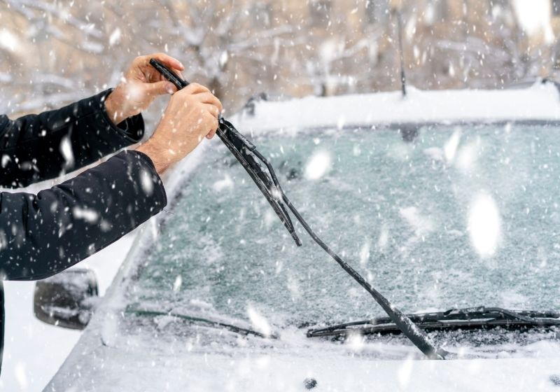 Man adjusting and cleaning wipers of car in snowy weather | Winterize Car | 13 Ways on How to Winterize a Car