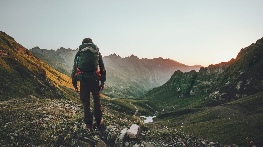 Man hiking at sunset mountains with heavy backpack | Homemade Wanderlust Gear List | XX Things You Should Have in Your Appalachian Trail Gear List | Featured