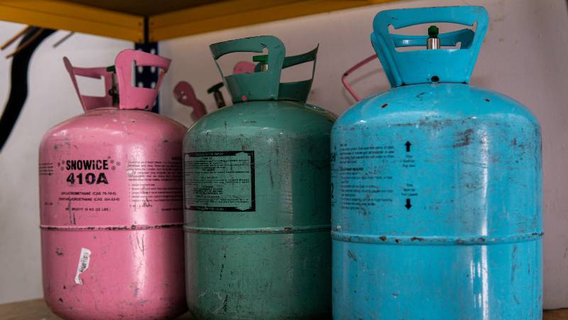 Various type of refrigerant gas tanks stored on the shelf inside | indoor propane heater