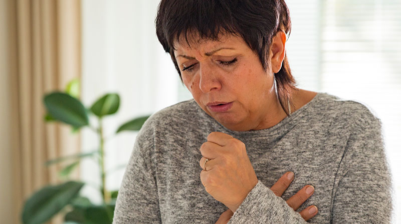 Sick mature woman with sore throat standing in living room at home | What to Do When Having a Heart Attack Alone | How to Survive a Heart Attack When Alone