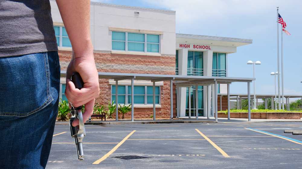 A young man with a pistol gun is standing in front of a high school preparing to commit a crime | Public Mass Shooting, Prevent Yourself From Becoming The Victim | featured