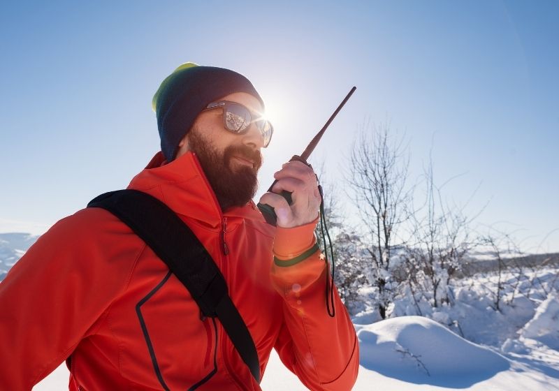 Rescue man talking with portable radio on mountain snow landscape | Avalanche Gear Checklist for Your Avalanche Survival Kit