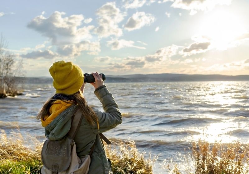 Young woman looking through binoculars at birds on the lake | Camping Near Valentine NE | Valentine Nebraska