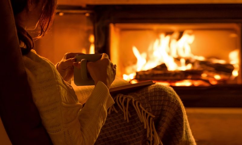 Young woman sitting home by fireplace | Alternative heat sources for power outages