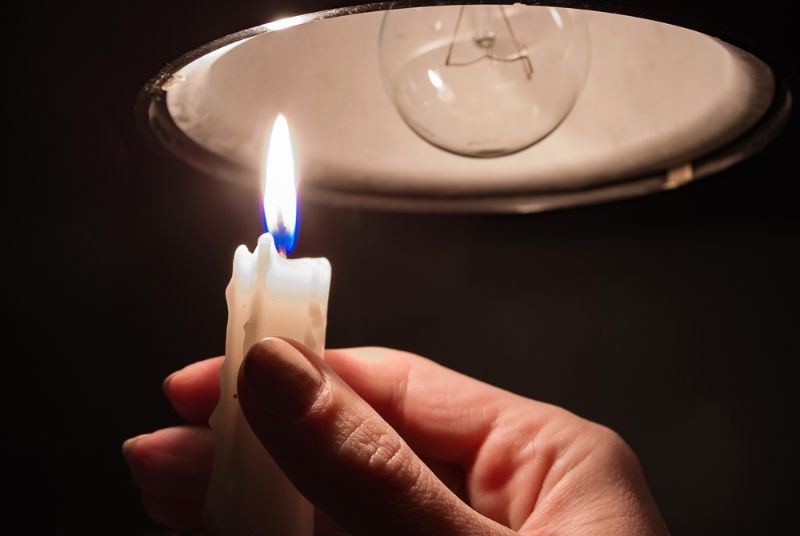 womans-hand-burning-candle-complete-darkness How to Keep Warm Without Electricity 