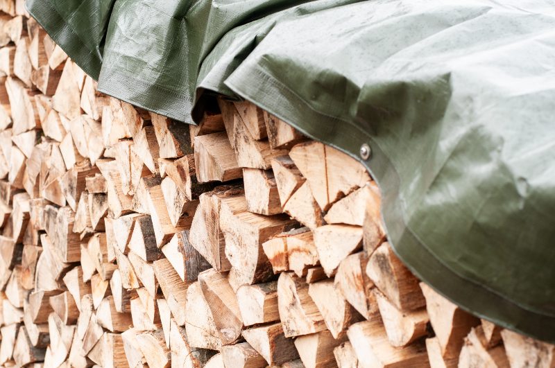 Close-Up of a Stack of Chopped Firewood Covered with Tarpaulin | How to Build a Bomb Shelter