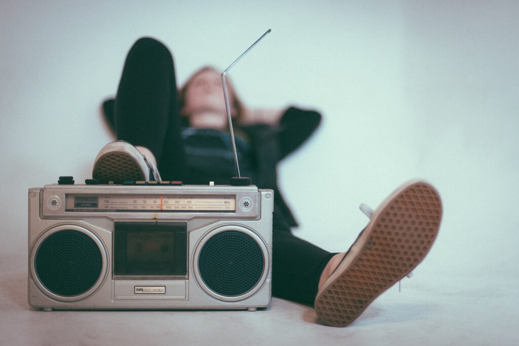 Radio woman laying on bed near gray radio