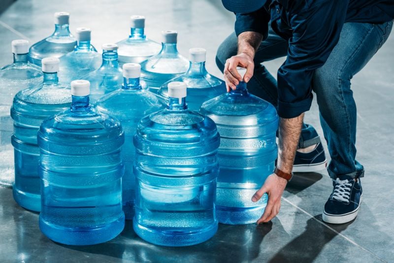 Man delivering large bottles drinking water What should I stockpile for economic collapse SS 1 1