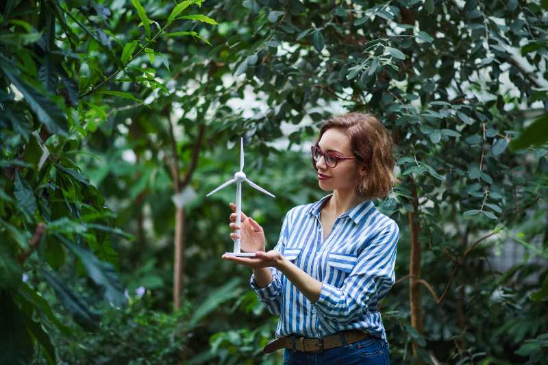 Young woman standing in botanical garden holding windmill model Environmental Policy ss 1